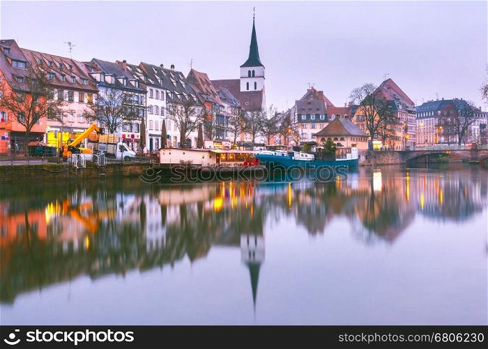 Picturesque quai des Pecheurs, Fisherman Wharf, and Protestant church of Saint Guillaume with mirror reflections in the river Ile during morning blue hour, Strasbourg, Alsace, France