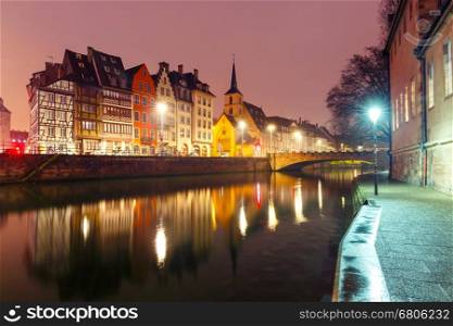 Picturesque quay and church of Saint Nicolas with mirror reflections in the river Ile during morning blue hour, Strasbourg, Alsace, France