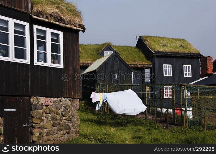 Picturesque residential area view with typical old black-tarred grass-roofed timber-walled houses with stone foundation on Tinganes in the old town of Torshavn the Captivating Capital of the Faroe Islands on Island Streymoy. Postcard motif.