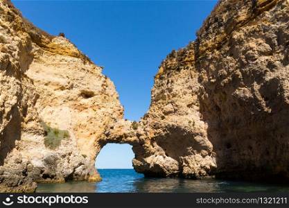 Picturesque rocky tunnel in the sea against blue sky, Portugal. Rocky tunnel in the sea