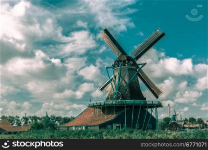 Picturesque rural landscape with windmills in Zaanse Schans close to river, Holland, Netherlands. Toning in cool tones