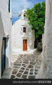 Picturesque scenic narrow Greek streets with traditional whitewashed houses with blue doors windows of Mykonos town and orthodox church in famous tourist attraction Mykonos island, Greece. Greek Mykonos street on Mykonos island, Greece