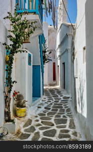 Picturesque scenic narrow Greek streets with traditional whitewashed houses with blue doors windows of Mykonos town in famous tourist attraction Mykonos island, Greece. Greek Mykonos street on Mykonos island, Greece