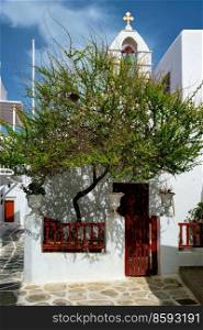 Picturesque scenic narrow Greek streets with traditional whitewashed houses with blue doors windows of Mykonos town and orthodox church in famous tourist attraction Mykonos island, Greece. Greek Mykonos street on Mykonos island, Greece