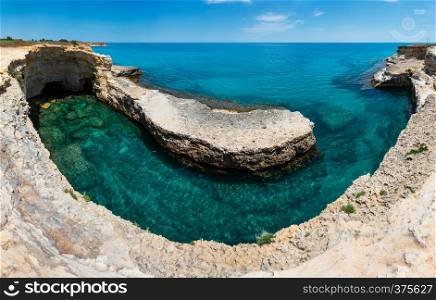 Picturesque seascape with white rocky cliffs, caves, sea bay and islets at Grotta del Canale, Sant'Andrea, Salento Adriatic sea coast, Puglia, Italy.