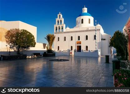 Picturesque square and white church of Panagia Platsani with blue dome in Oia or Ia on the island Santorini in the morning, Greece. Oia or Ia at sunset, Santorini, Greece