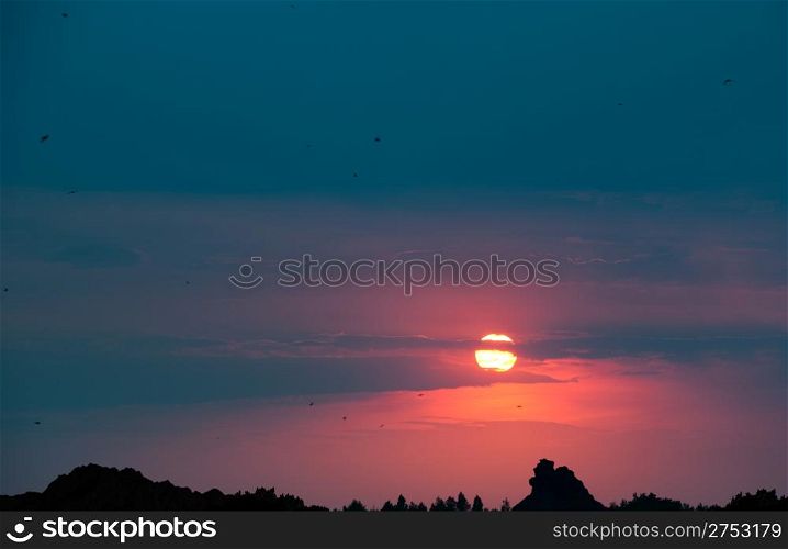 Picturesque sunset.Above mountain and a wood. Silhouette the image