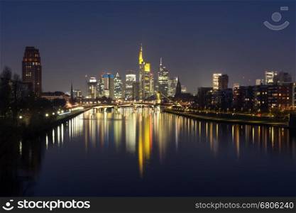 Picturesque view of business district with skyscrapers and mirror reflections in the river at dark night, Frankfurt am Main, Germany