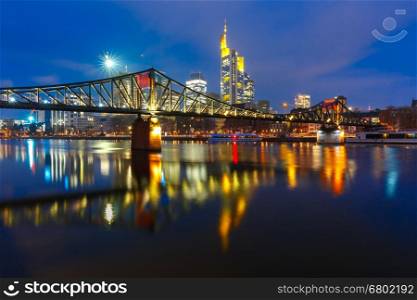 Picturesque view of Frankfurt am Main skyline and Eiserner Steg bridge with mirror reflections in the river during morning blue hour, Germany