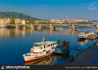 Picturesque view of the boats on Vltava River, Jiraskuv bridge and Prague Castle in Prague, Czech Republic