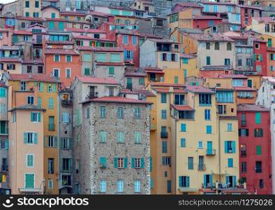 Picturesque view of the multicolored medieval houses in the historic part of the city. Menton. France.. Menton. Antique multi-colored facades of medieval houses on the shore of the bay.
