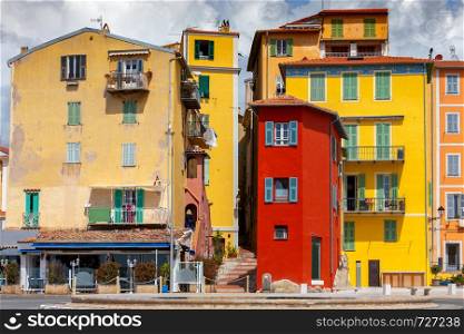 Picturesque view of the multicolored medieval houses in the historic part of the city. Menton. France. Cote d'Azur.. Menton. Antique multi-colored facades of medieval houses on the shore of the bay.