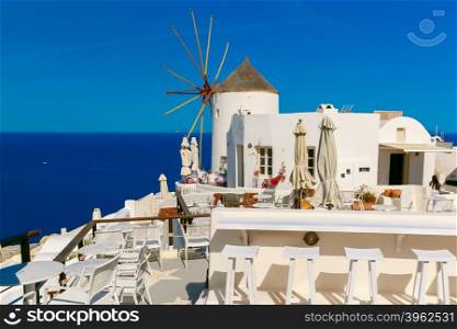 Picturesque view of windmill, empty restaurant and white houses in Oia or Ia on the island Santorini, Greece