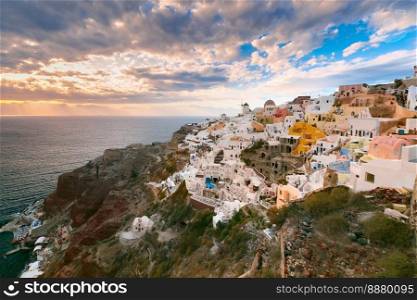 Picturesque view, Old Town of Oia or Ia on the island Santorini, white houses, windmills and church with blue domes at sunset, Greece. Oia or Ia at sunset, Santorini, Greece