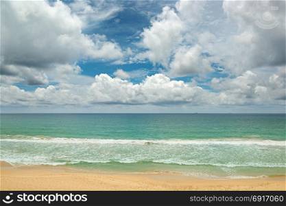 Picturesque waves in the ocean, yellow sand and blue sky.
