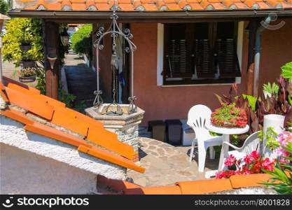 Picturesque well and flower decoration near residential house in small town Sant Andreas on Elba Island, Italy