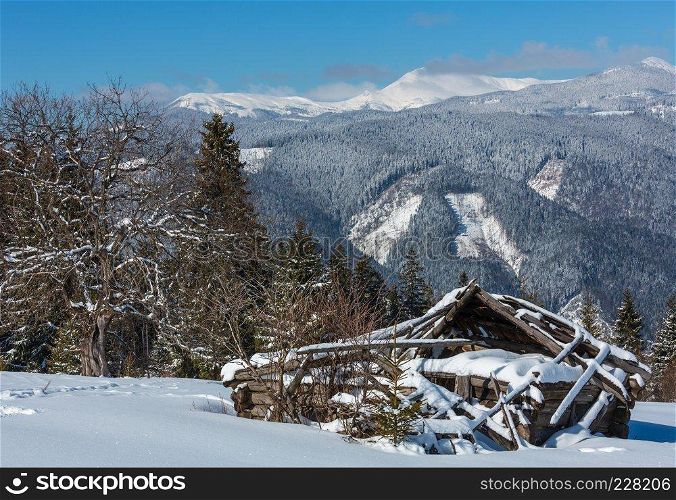 Picturesque winter mountain view from Skupova mountain slope, Ukraine. Old ruined wooden shed and view to Chornohora ridge and Pip Ivan mountain top with observatory building, Carpathian.