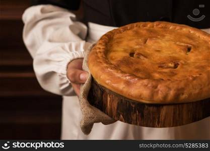 Pie from potato meat cheese and vegetables. Pie from potato meat cheese and vegetables. Freshly baked pie in hands of woman in uniform