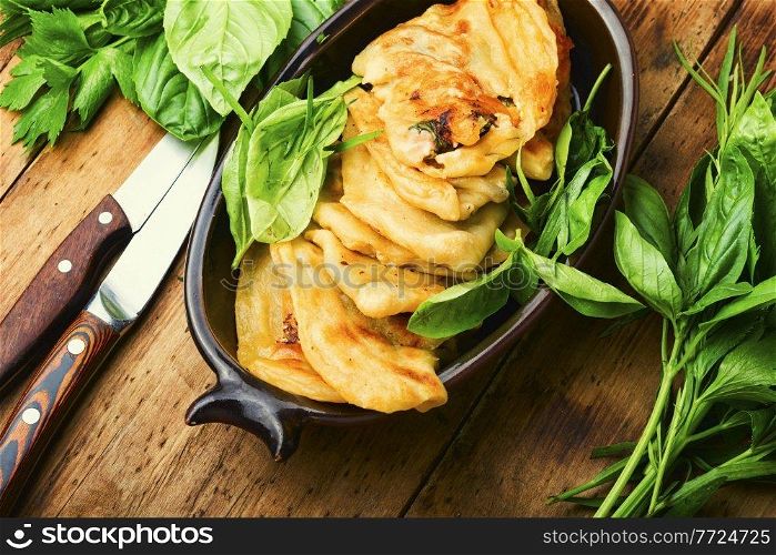 Pie stuffed with spring greens and cheese. Homemade qutabs or kutab. Azeyrbajan food. Tasty qutab with young greens on wooden table