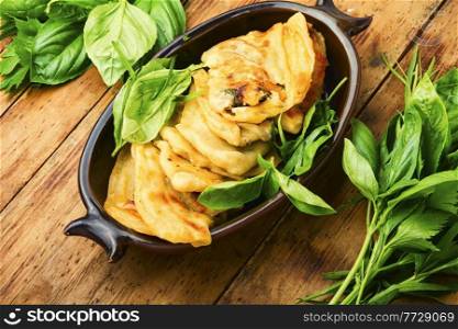 Pie stuffed with spring greens and cheese. Homemade qutabs or kutab. Azeyrbajan food.Flat lay. Tasty Azerbaijani qutab with young greens,wooden table