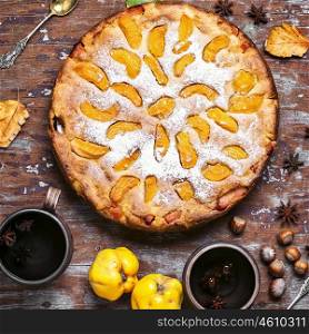 Pie with autumn quinces. Autumn pie with slices of quince and warming cup of tea