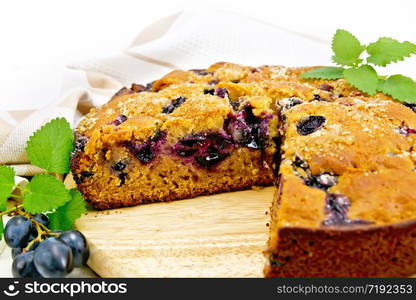 Pie with black grapes and honey, mint, napkin on a light wooden board background