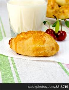 Pie with cherries on a paper napkin, a glass of milk on a linen tablecloth background