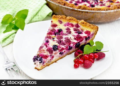 Pie with raspberries, currants and cream sauce in a plate, napkin and mint on wooden board background