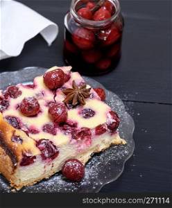 piece of a cheesecake with cherries on a glass plate and a jar with  berries
