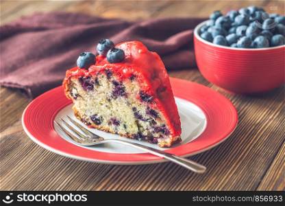 Piece of cake with blueberries on the plate on the wooden background
