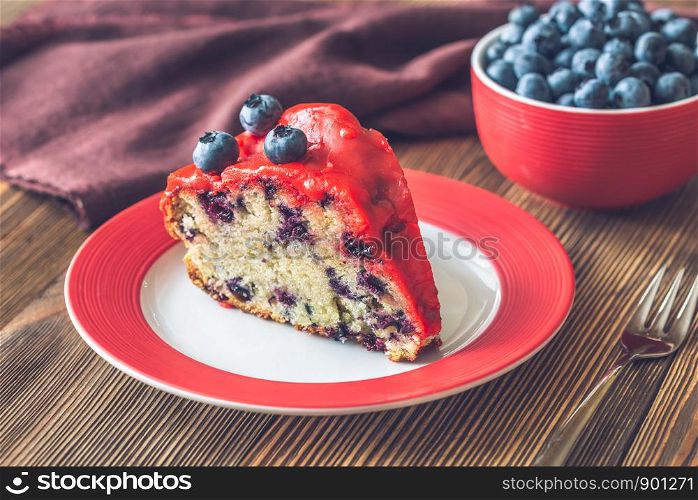 Piece of cake with blueberries on the plate on the wooden background