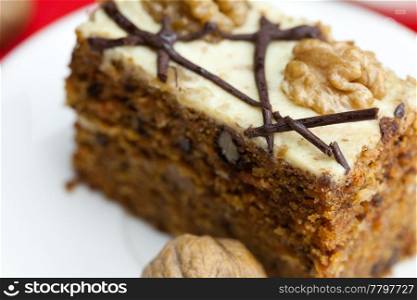 Piece of cake with nuts lying on the plate on a red background