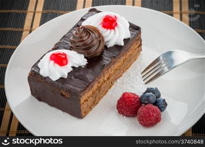 Piece of chocolate cake with berries on white plate.