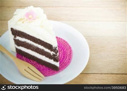 Piece of chocolate cake with flower on wood background&#xA;