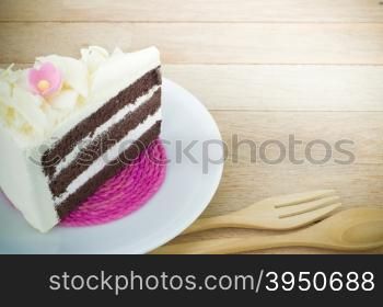 Piece of chocolate cake with flower on wood background&#xA;