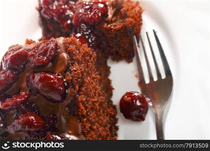 Piece of chocolate cake with icing and cherry on white background