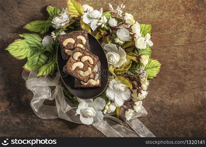 Piece of chocolate cashew nut cake on plate over wooden table. chocolate macadamia cake