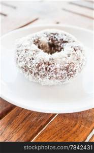 Piece of chocolate coconut donut on white plate, stock photo
