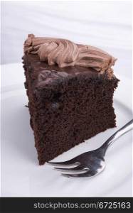 Piece of dark chocolate cake on white background