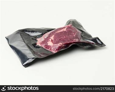 piece of fresh beef meat packed in a vacuum plastic bag, top view