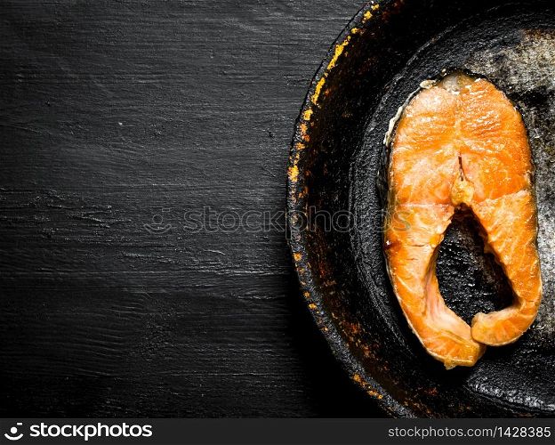 piece of grilled salmon in an old pan. On the black chalkboard.. piece of grilled salmon in an old pan.