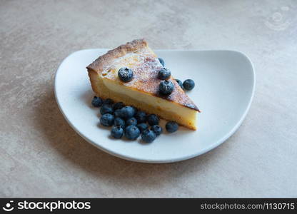 Piece of homemade cake on unusual plate shape with berry decorate on top. Piece of homemade cake with berry decorate on top