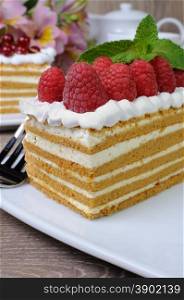Piece of honey cake with whipped cream and raspberries