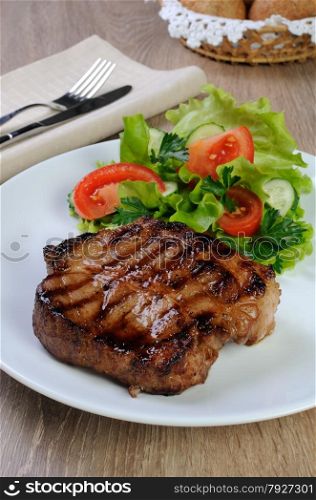 piece of juicy pork steak grilled with a salad