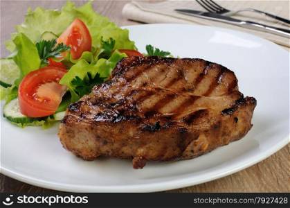 piece of juicy pork steak grilled with a salad