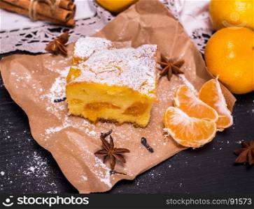 piece of mandarin cake on brown kraft paper and fresh tangerines