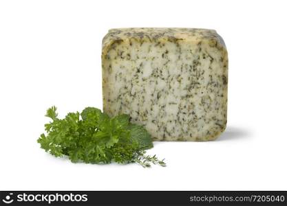 Piece of mature Dutch goats cheese witha variety of green herbs isolated on white background