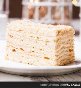 Piece of napoleon cake on a plate, over defocused light background