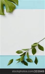 Piece of paper with empty space under the text on a blue background decorated with leaves flat lay. Postcard decorated leavs