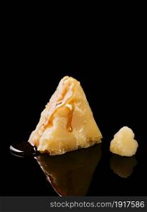 Piece of parmigiano cheese close up, honey flows on the cheese, selective focus. Cheese is reflected on a dark table.
